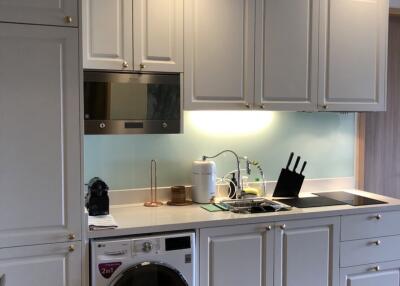 Modern kitchen with white cabinetry, built-in appliances, and washing machine