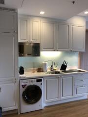 Modern kitchen with white cabinetry, built-in appliances, and washing machine