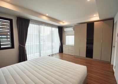 Modern bedroom with large windows, wooden flooring, and spacious wardrobes