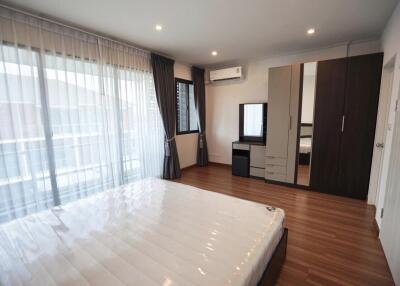 Spacious bedroom with large windows, wooden floors, and a bed