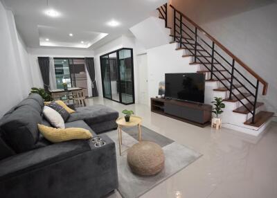 Spacious living room with gray sofa, TV, and staircase