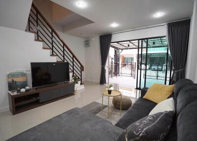 Modern living room with TV, sofa, and sliding glass doors with view of patio