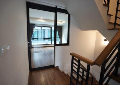 Concise view of an interior staircase leading to a hallway with large windows and wooden flooring.