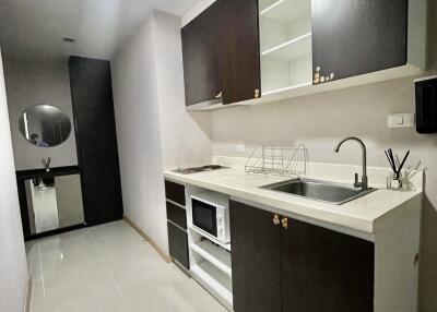 Modern narrow kitchen with dark cabinets and white countertops