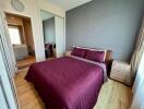 Bedroom with large bed, wooden flooring, and view into adjoining bathroom