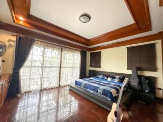 Spacious bedroom with large windows and wooden ceiling beams