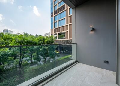 Modern balcony with glass railing and views of greenery and neighboring buildings