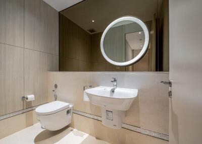 Modern bathroom with wall-mounted toilet and sink, large mirror, and wooden paneling