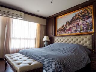 Bedroom with large bed, upholstered bench, and artwork