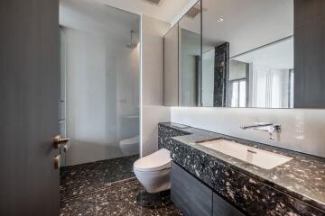 Modern bathroom with black marble countertop and glass shower enclosure