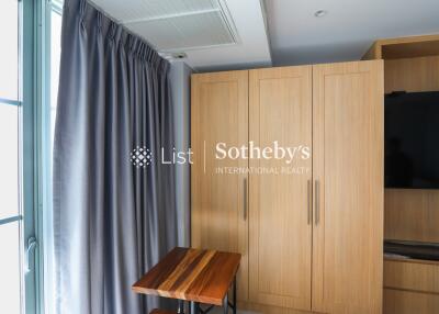 Bedroom with wooden closet, television, and window with curtains