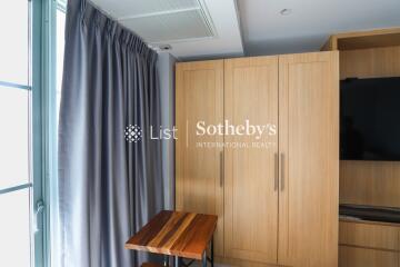 Bedroom with wooden closet, television, and window with curtains