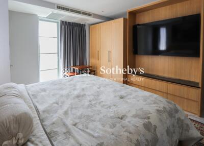 Spacious bedroom with large wardrobe and mounted TV