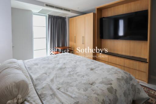 Spacious bedroom with large wardrobe and mounted TV