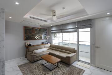 Modern living room with a sectional sofa, coffee table, and balcony access