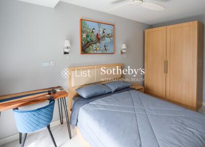 Bedroom with modern wooden wardrobe and bed, desk, blue chair, painting on the wall, and overhead lighting