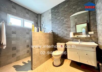 Bathroom with modern design, shower area, vanity, toilet, and tiled walls