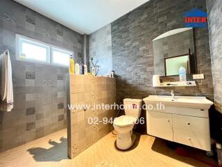 Bathroom with modern design, shower area, vanity, toilet, and tiled walls