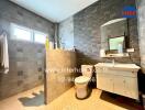 Bathroom with modern design, shower area, vanity, toilet, and tiled walls