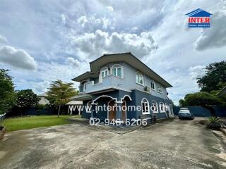 Two-story house with driveway and surrounding greenery