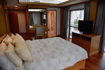 Spacious bedroom with large bed, TV, and dressing table