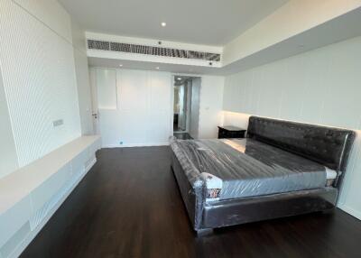 Modern bedroom with dark wood flooring and a large bed with tufted headboard.