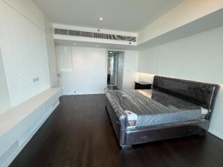 Modern bedroom with dark wood flooring and a large bed with tufted headboard.