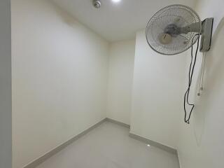 Small empty room with a wall-mounted fan and tile flooring