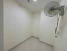 Small empty room with a wall-mounted fan and tile flooring