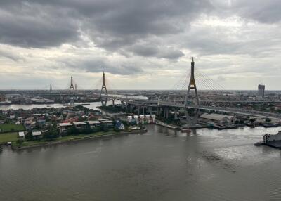 View of a river with a bridge and buildings in the background under a cloudy sky