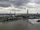 View of a river with a bridge and buildings in the background under a cloudy sky