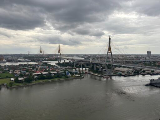 View of a river with a bridge and buildings in the background under a cloudy sky