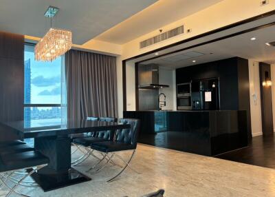 Modern dining area with chandelier, adjacent to an open kitchen.