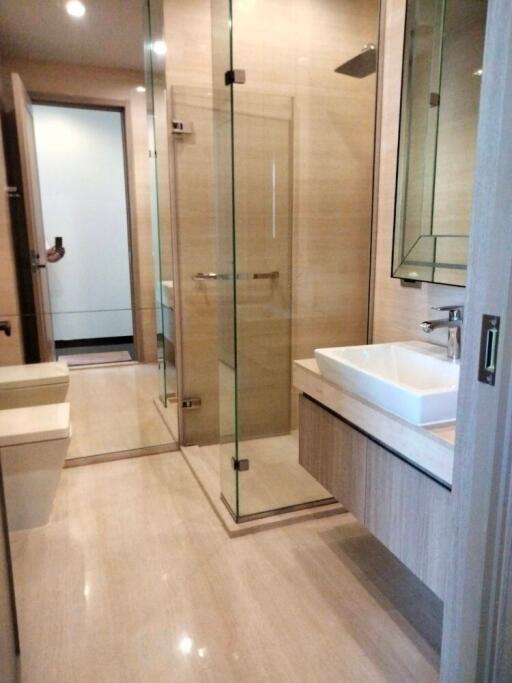 Modern bathroom with glass shower, floating sink, and light wood finishes