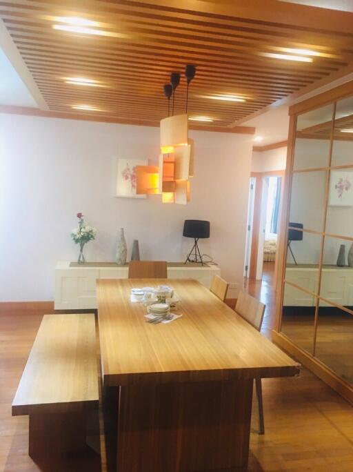 Modern dining room with wooden table and bench, pendant lights, and decorative elements