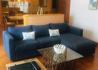 Modern living room with a large blue sectional sofa and a glass coffee table