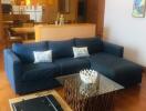 Modern living room with a large blue sectional sofa and a glass coffee table