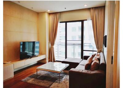 Modern living room with sofa, TV, coffee table, and large windows.