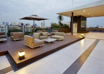 Modern rooftop terrace with city views, seating area, and umbrellas.