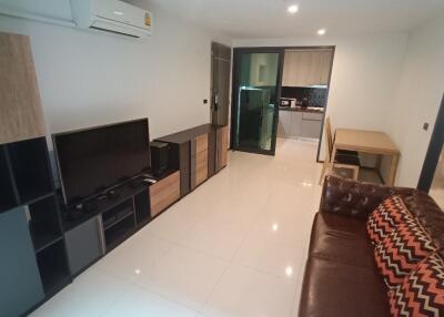 Main living space with TV, air conditioning, modern furniture, and adjacent kitchen and bathroom