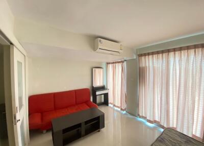 Living room with red couch, air conditioner, and large windows