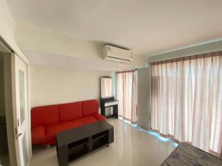 Living room with red couch, air conditioner, and large windows