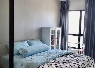 A cozy bedroom with a double bed, light blue beddings, and a glass door.