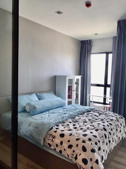 A cozy bedroom with a double bed, light blue beddings, and a glass door.