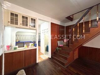 Staircase leading from living space to upper level with under-stairs storage and adjacent kitchen