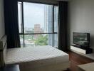 Bedroom with large window, bed, nightstand, and TV