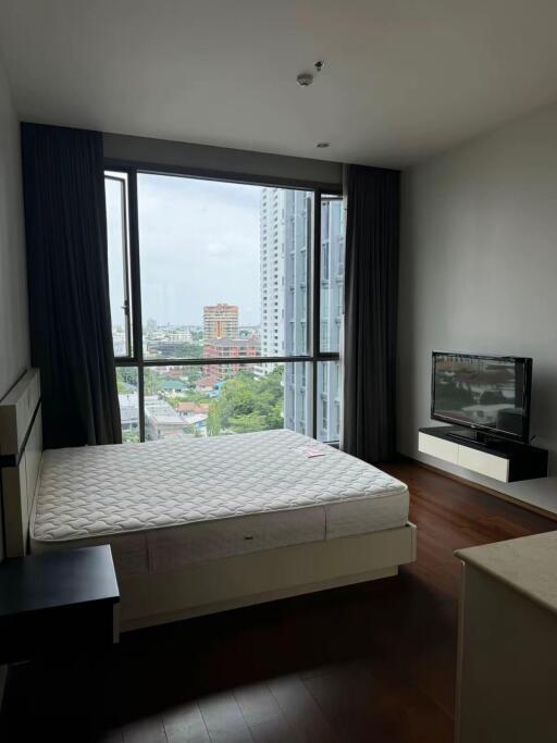 Bedroom with large window, bed, nightstand, and TV