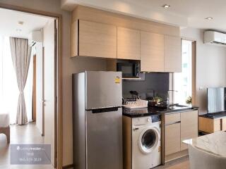 Modern kitchen with fridge, washing machine, and overhead cabinets