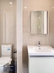 Modern bathroom with a sink, toilet, and a mirror cabinet