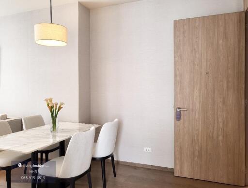 Dining area with a marble table, cushioned chairs, and a modern pendant light